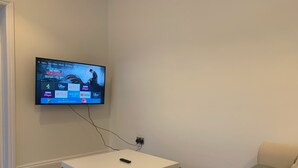 A living room with a mounted TV displaying a streaming service interface. - Roath Retreat (Cardiff)