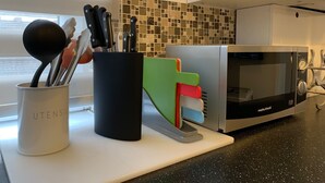 A kitchen with a microwave, utensils in a holder, and a tiled backsplash. - Roath Retreat (Cardiff)