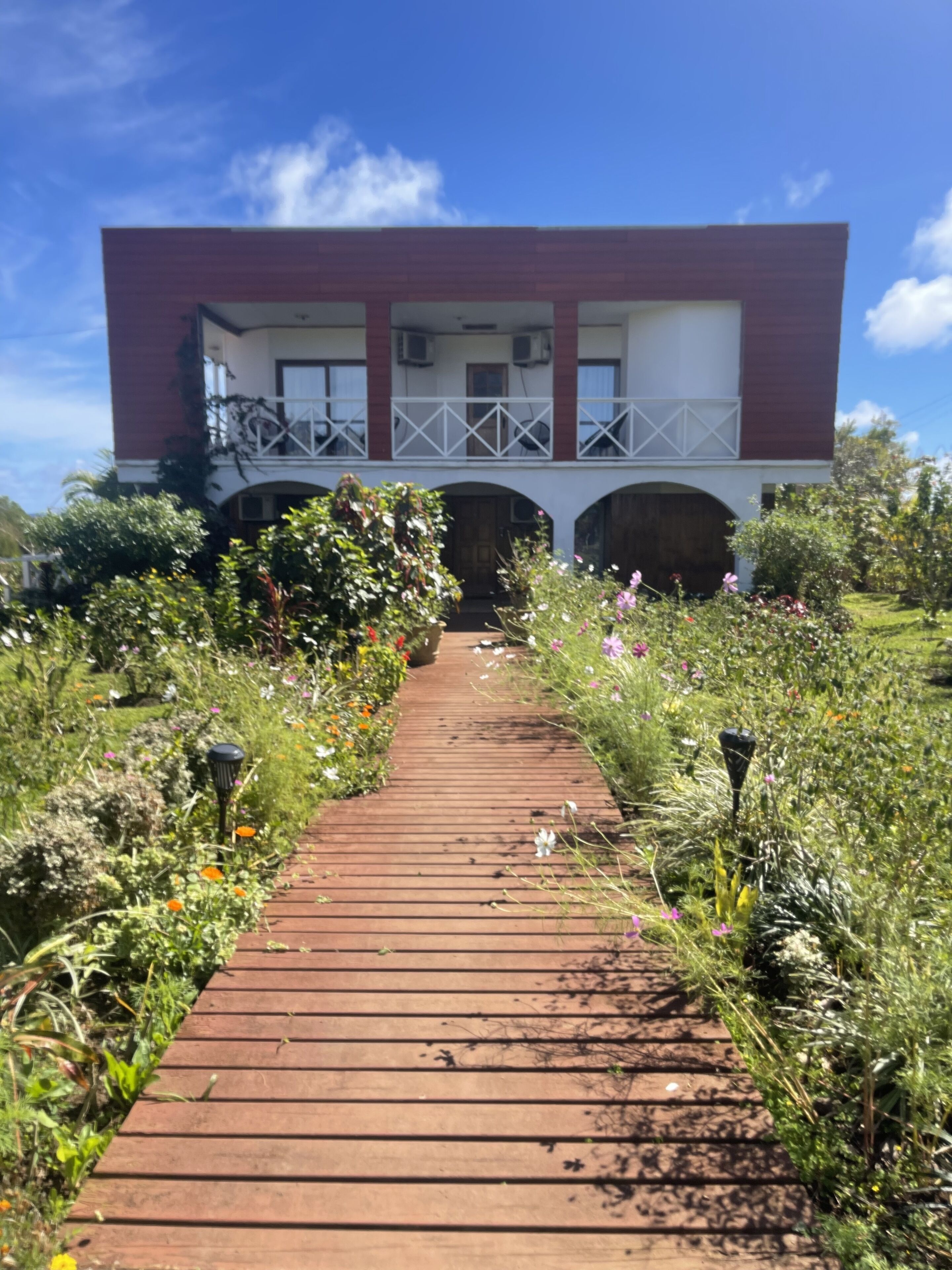 Un sendero que lleva a un edificio con balcón y entrada cubierta.