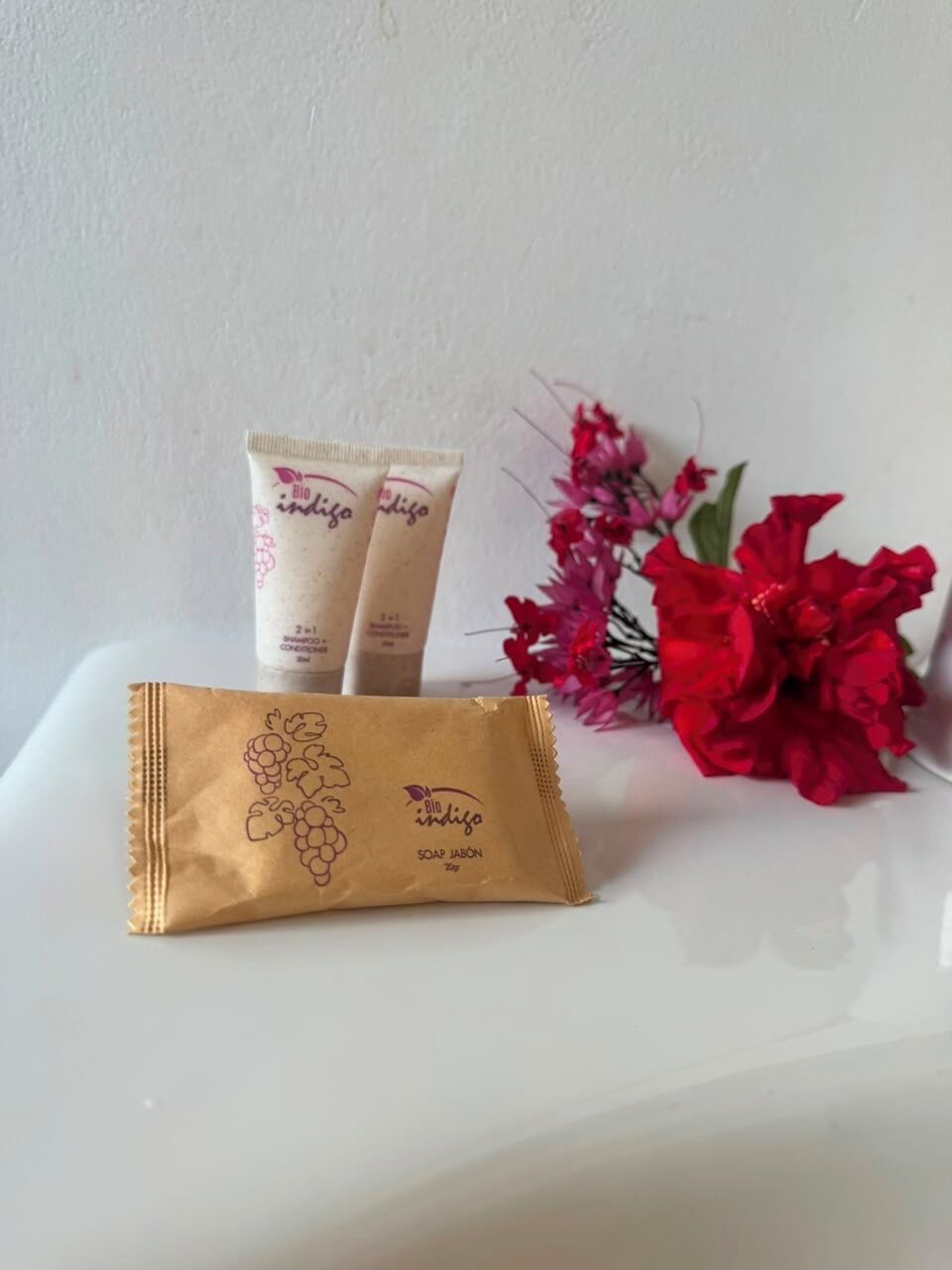 A bathroom with a white sink, two soap bars, and a brown paper bag with a grape design.