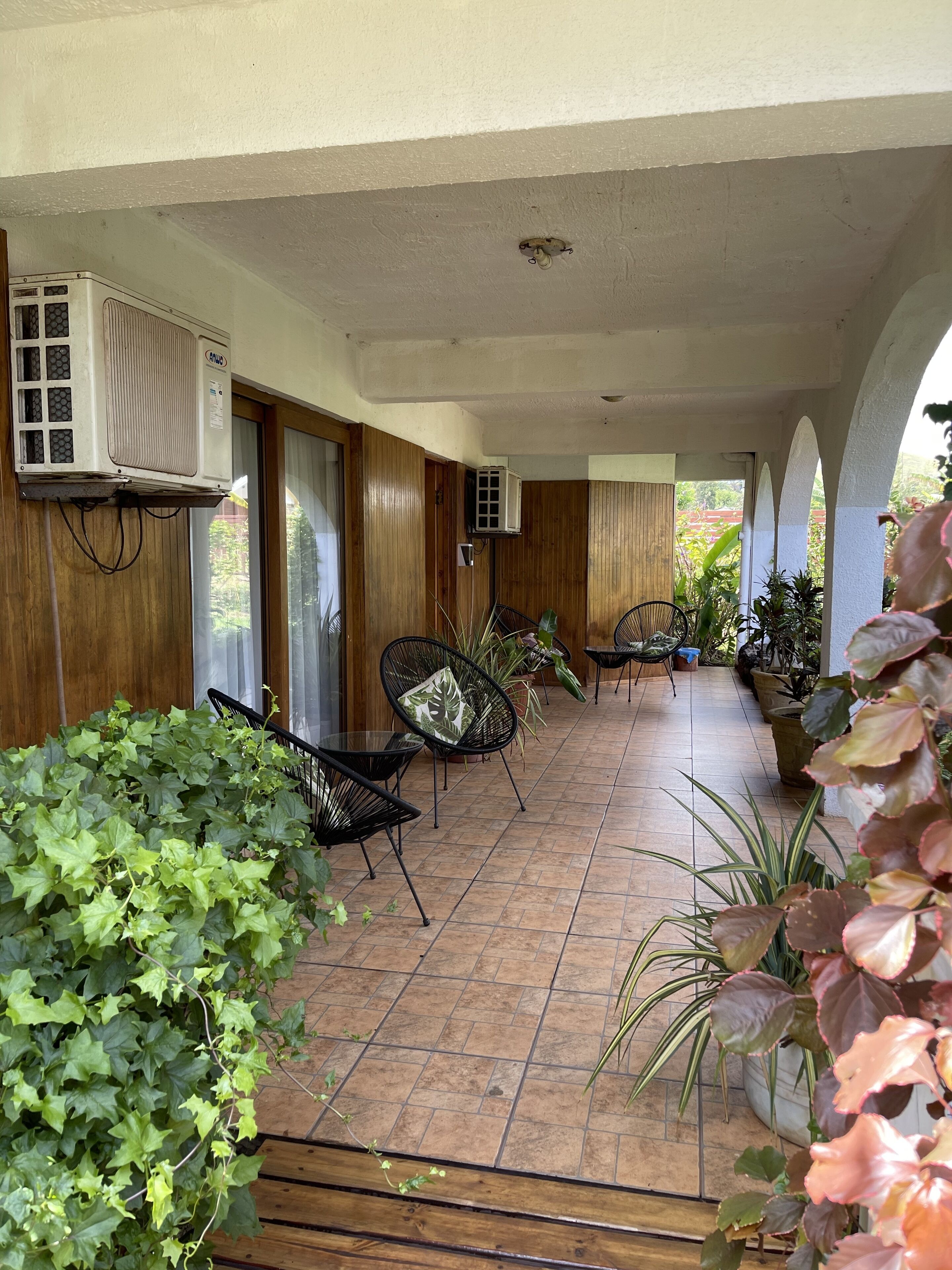 Un espacio de patio cubierto con piso de baldosas, paredes de madera y varias sillas y mesas.