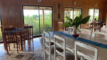 Un comedor con paredes de madera, piso de baldosas y un ventanal que ofrece vistas a la vegetación.