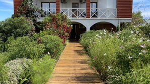 A wooden pathway leading to a building with a balcony and a covered entrance. - Hotel Teanehi (Hanga Roa)