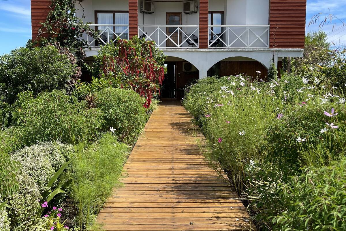 Een houten pad dat leidt naar een gebouw met een balkon en een overdekte ingang.