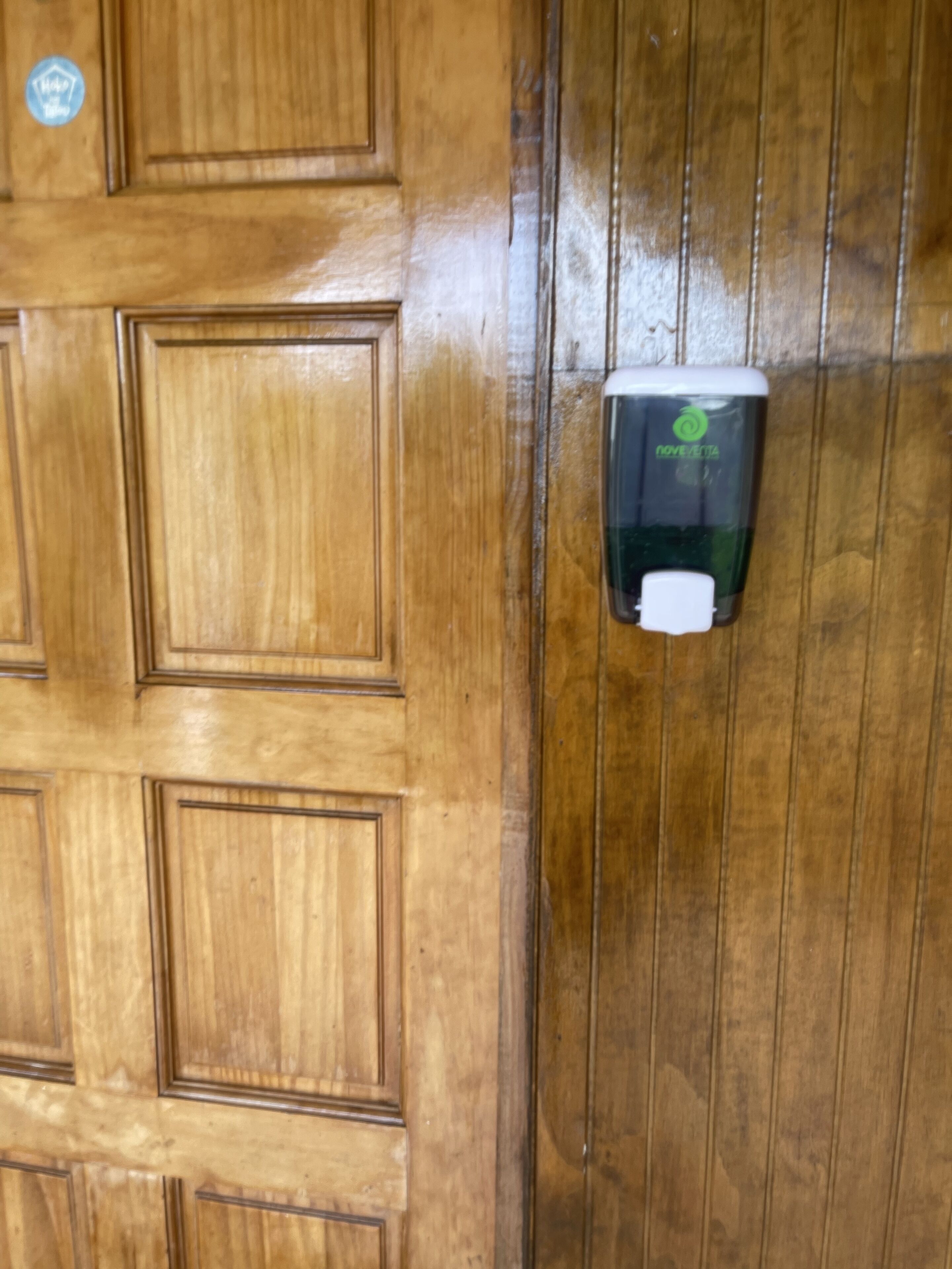 Una puerta de madera con dispensador de gel antibacterial.