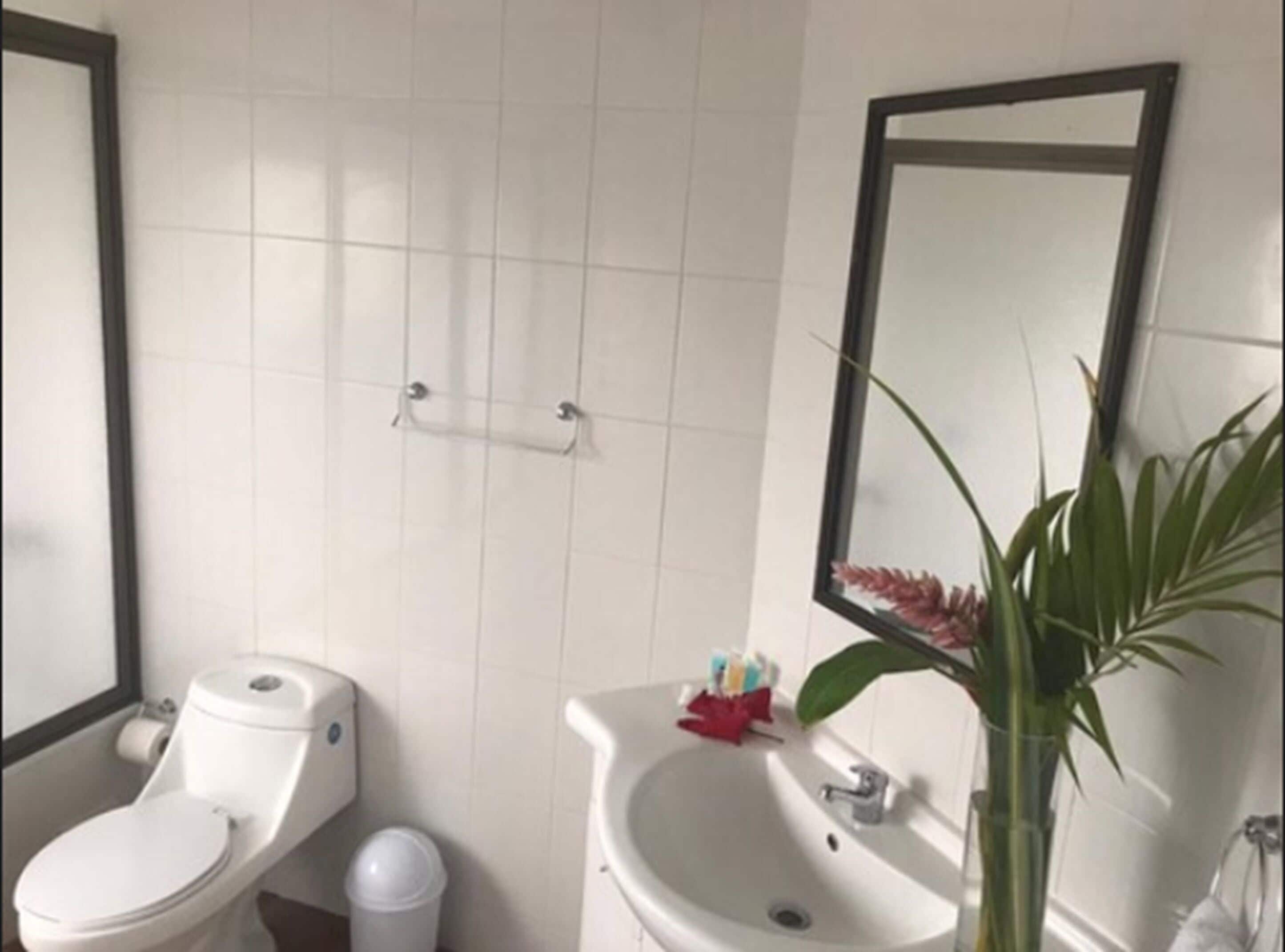 A bathroom with two sinks, a toilet, and a mirror.