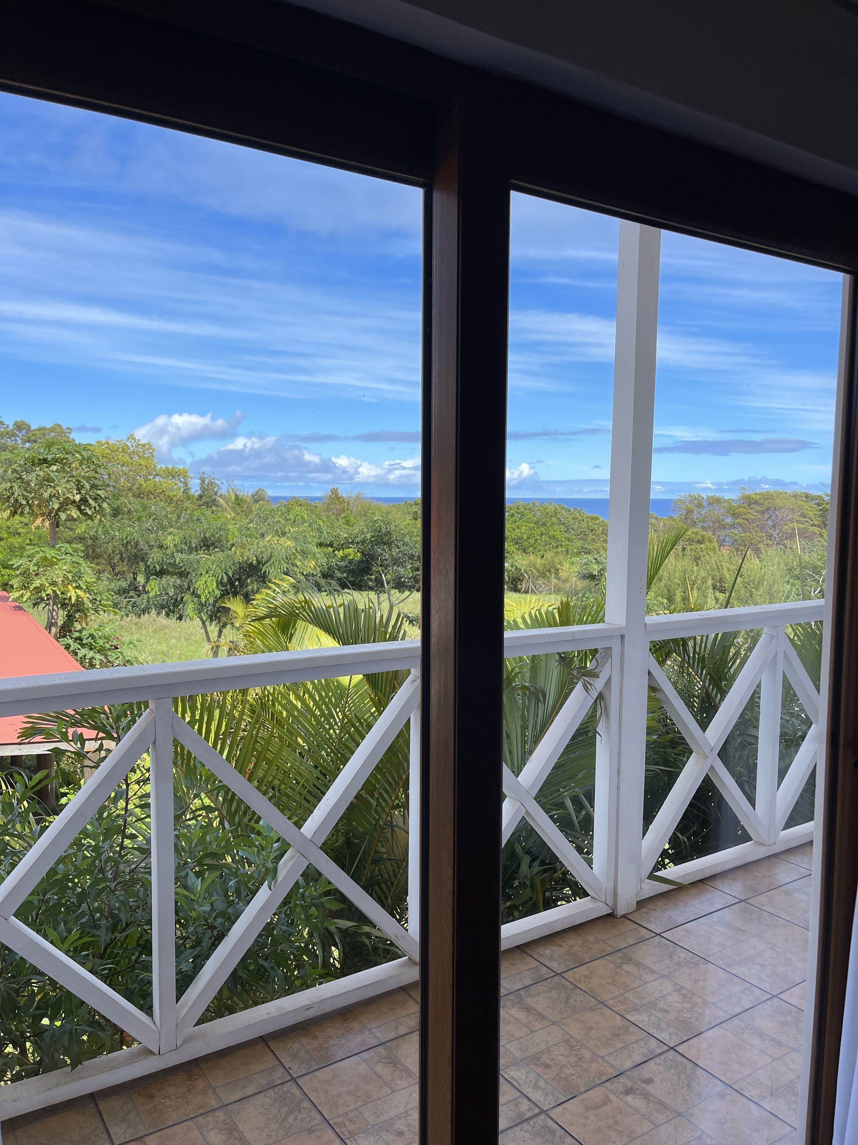A balcony with a view of lush greenery and a clear blue sky.