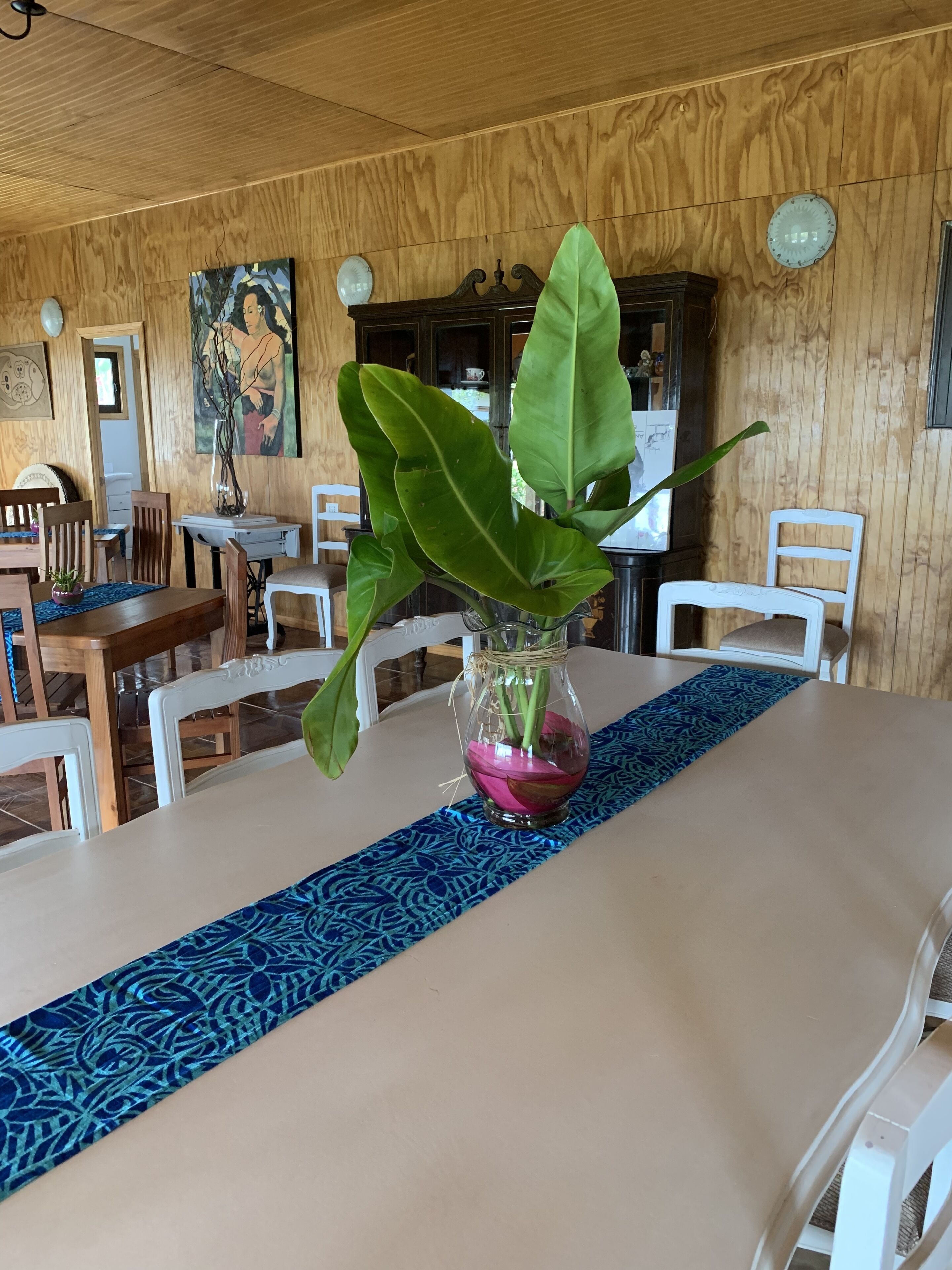 Un comedor con una mesa dispuesta para dos personas, un florero con planta y paneles de madera.