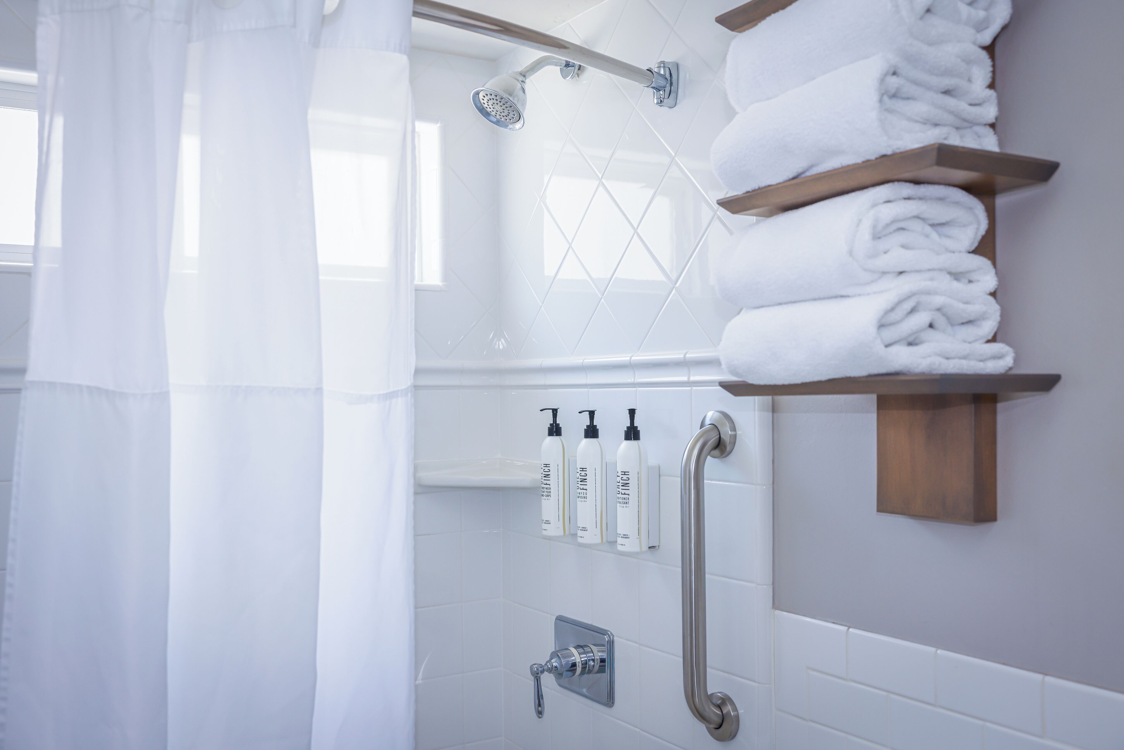 Ein Badezimmer mit Dusche, Handtuchhalter und Pflegeprodukten.