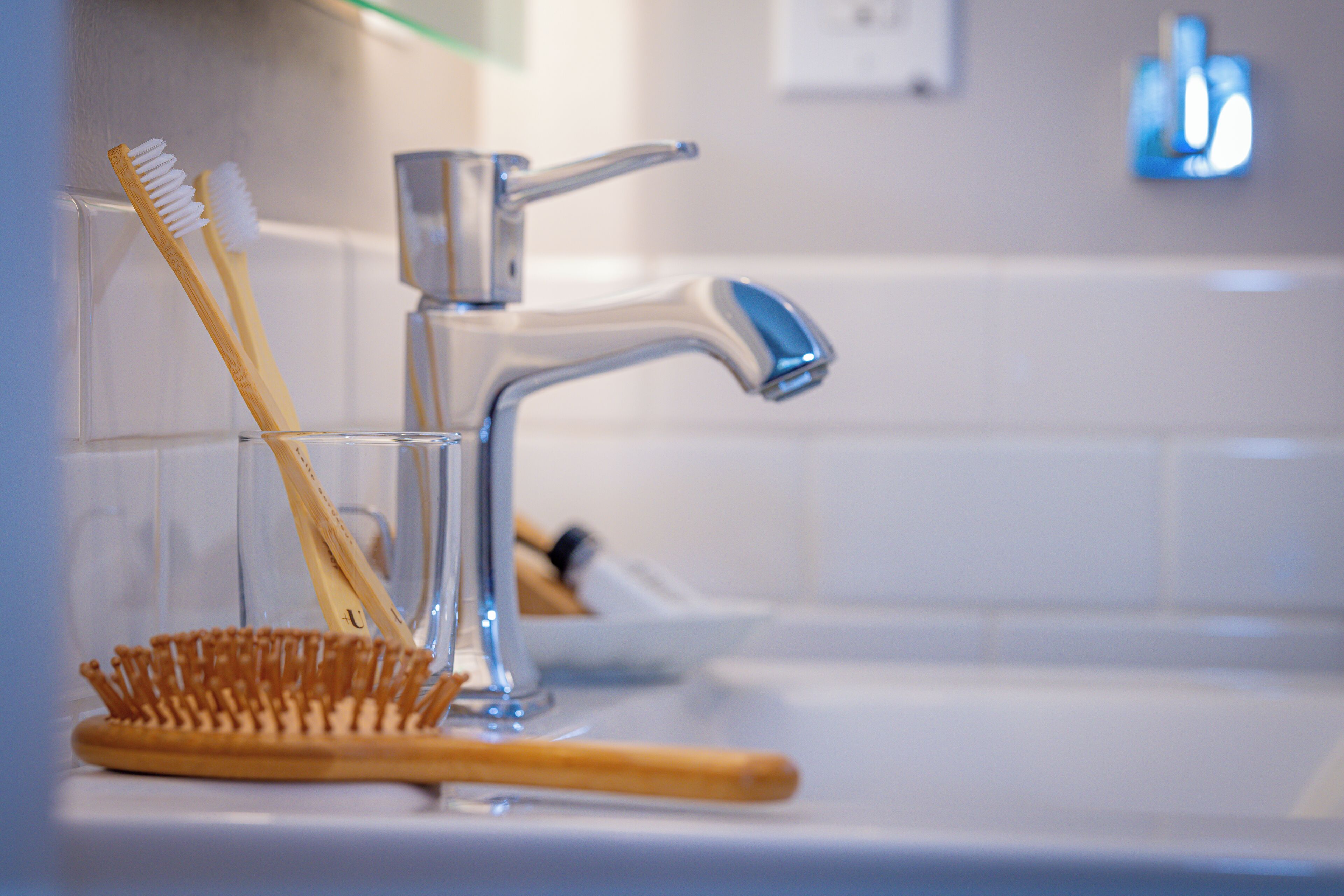 Un lavabo de salle de bain avec un robinet chromé, une brosse à dents et une brosse en bois.