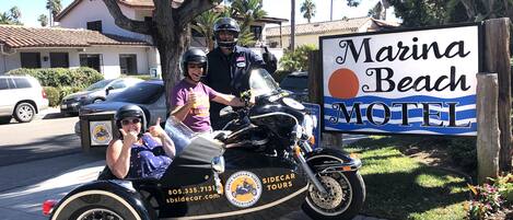 A sign for Marina Beach Motel with a sidecar motorcycle parked in front.