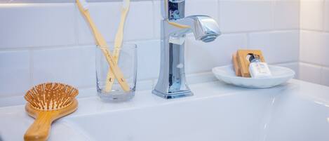 A bathroom sink with a toothbrush holder, a toothbrush, and a hairbrush.
