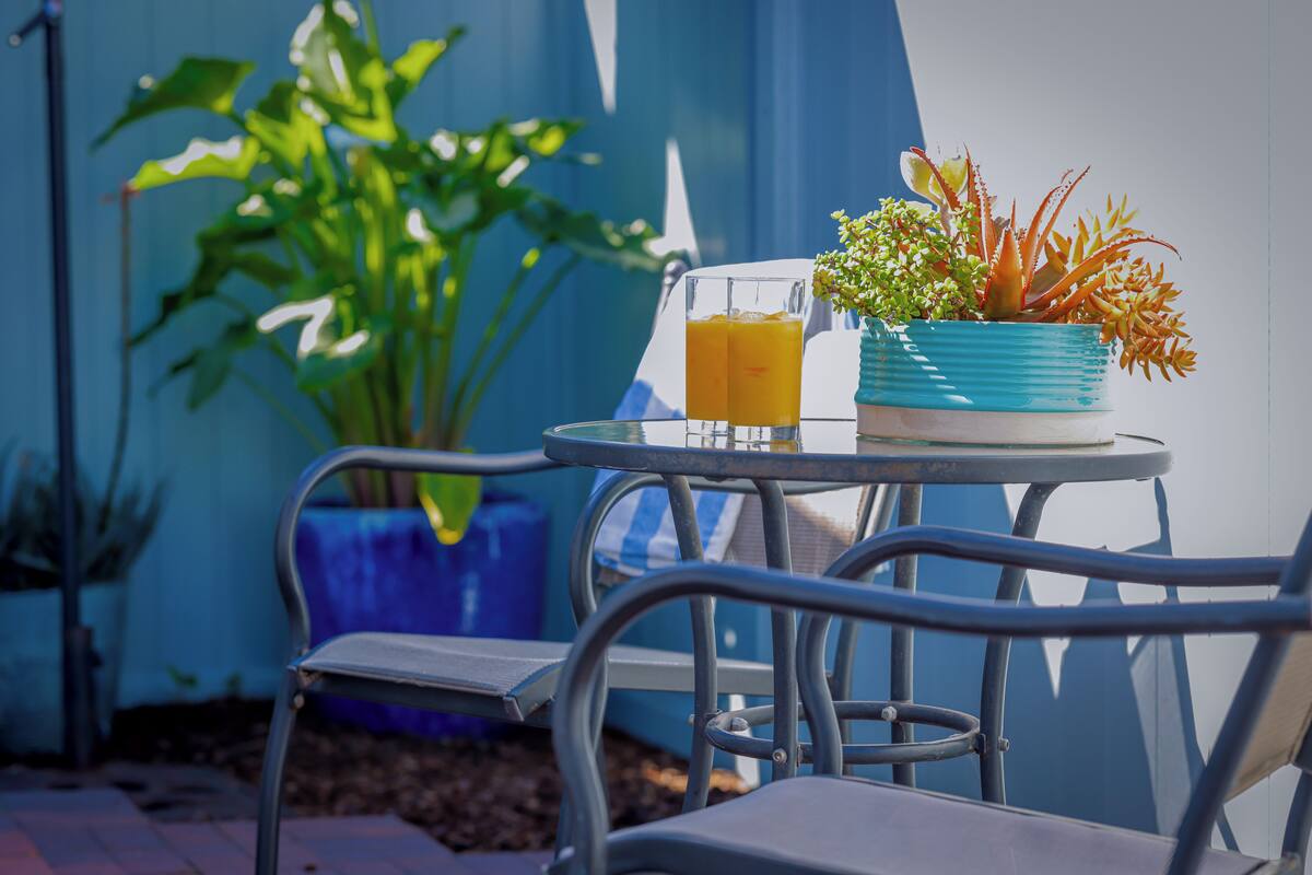 A metal table with a glass of orange juice and a potted plant.