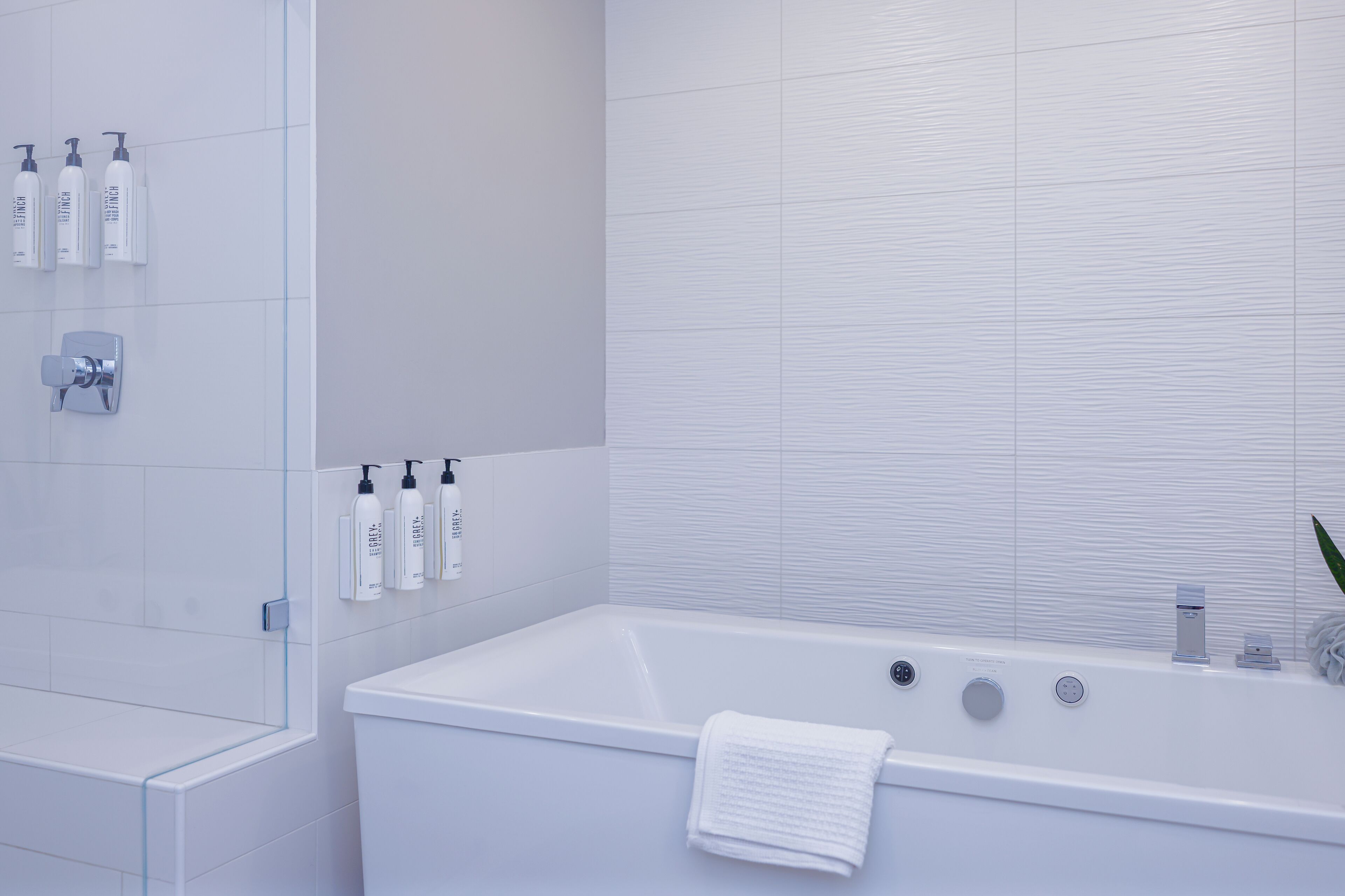 Un baño moderno con bañera, cabina de ducha de vidrio y artículos de aseo en la pared.