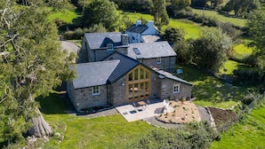 Una casa de piedra con una puerta de madera grande y un patio con mobiliario exterior.