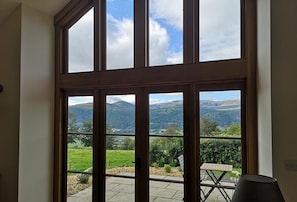 Quarto com uma janela grande que oferece vista para uma paisagem verde e montanhas.