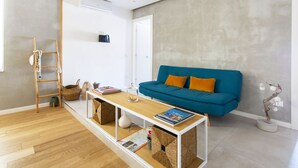 Un salon moderne avec un canapé bleu, une table basse en bois et une échelle appuyée contre le mur.