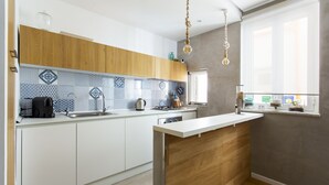 Une cuisine moderne avec des meubles blancs et en bois, un pare-feu en carrelage et une fenêtre donnant sur un beau paysage.