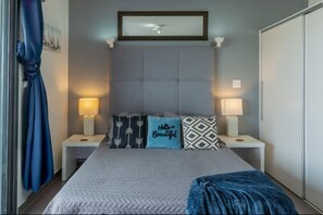 Une chambre à coucher comprenant un lit, deux tables de chevet, une tête de lit et une armoire.