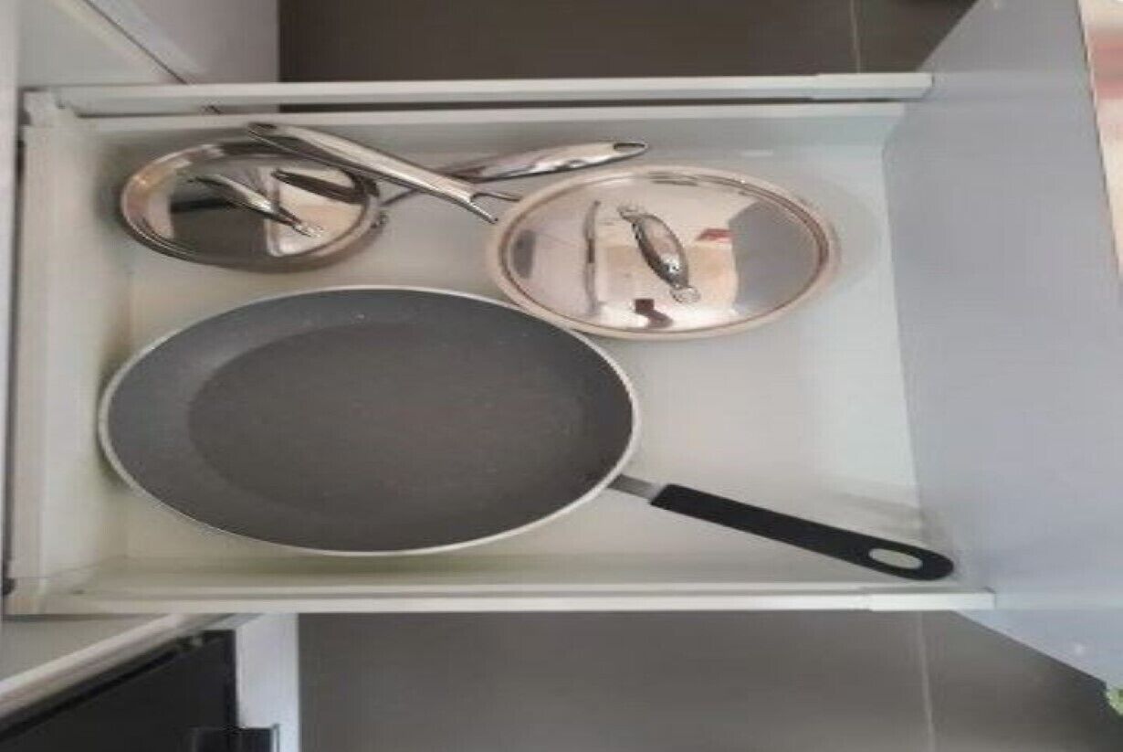 Un tiroir de cuisine contenant une poêle, une casserole et une pince.