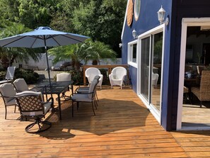 A wooden deck with outdoor furniture, including a table and chairs, and a blue umbrella.
