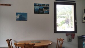 Un comedor con una mesa y sillas de madera, una ventana con vistas a la vegetación y una pared decorada con un collage de fotos.