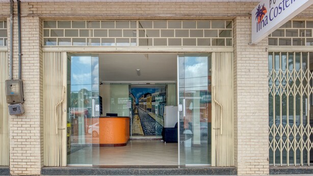 A hotel entrance with a reception desk, glass doors, and a sign reading "Pousada da Costeira". - Pousada Vilas Costeira (São Luís)