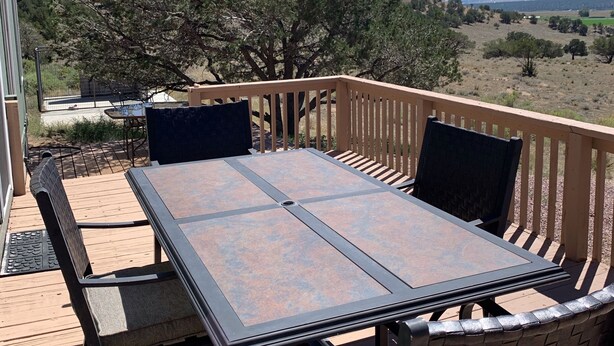 An outdoor deck with a table and chairs, overlooking a landscape with trees and distant mountains. - Great for ATV's and TOY'S!  Rent 6 nights and 7th is free! (Buena Vista)
