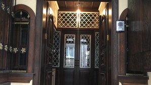Una entrada de madera con puerta de cristal, un cartel sobre la puerta y una lámpara encima.