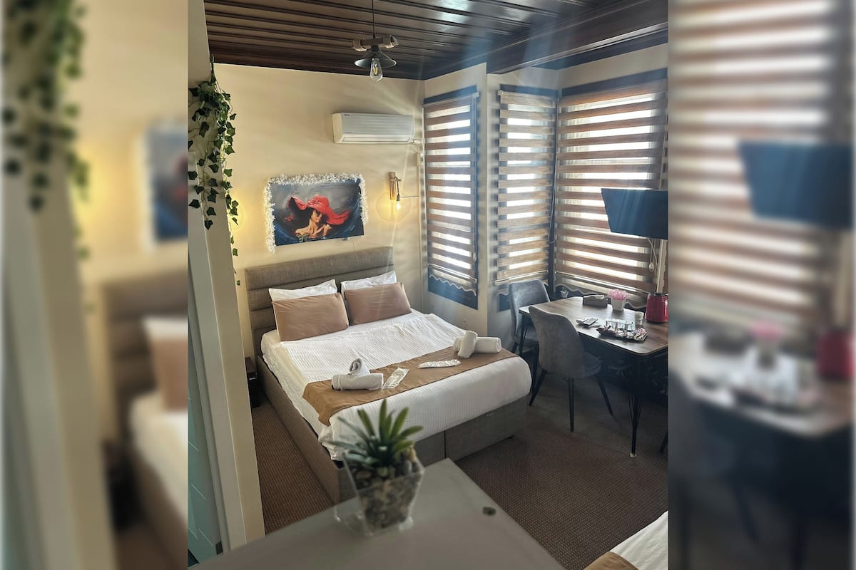 Una habitación de hotel moderna con cama, mesita de noche y escritorio con silla.