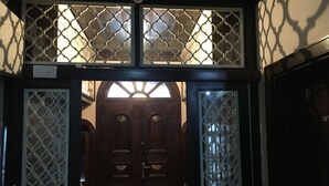 Una puerta de madera oscura con tallas intrincadas y un panel de vidrio decorativo en la parte superior.