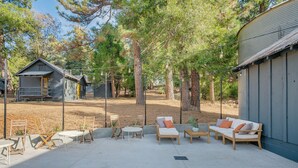 A patio area with outdoor furniture, a small table, and a fenced yard with trees.