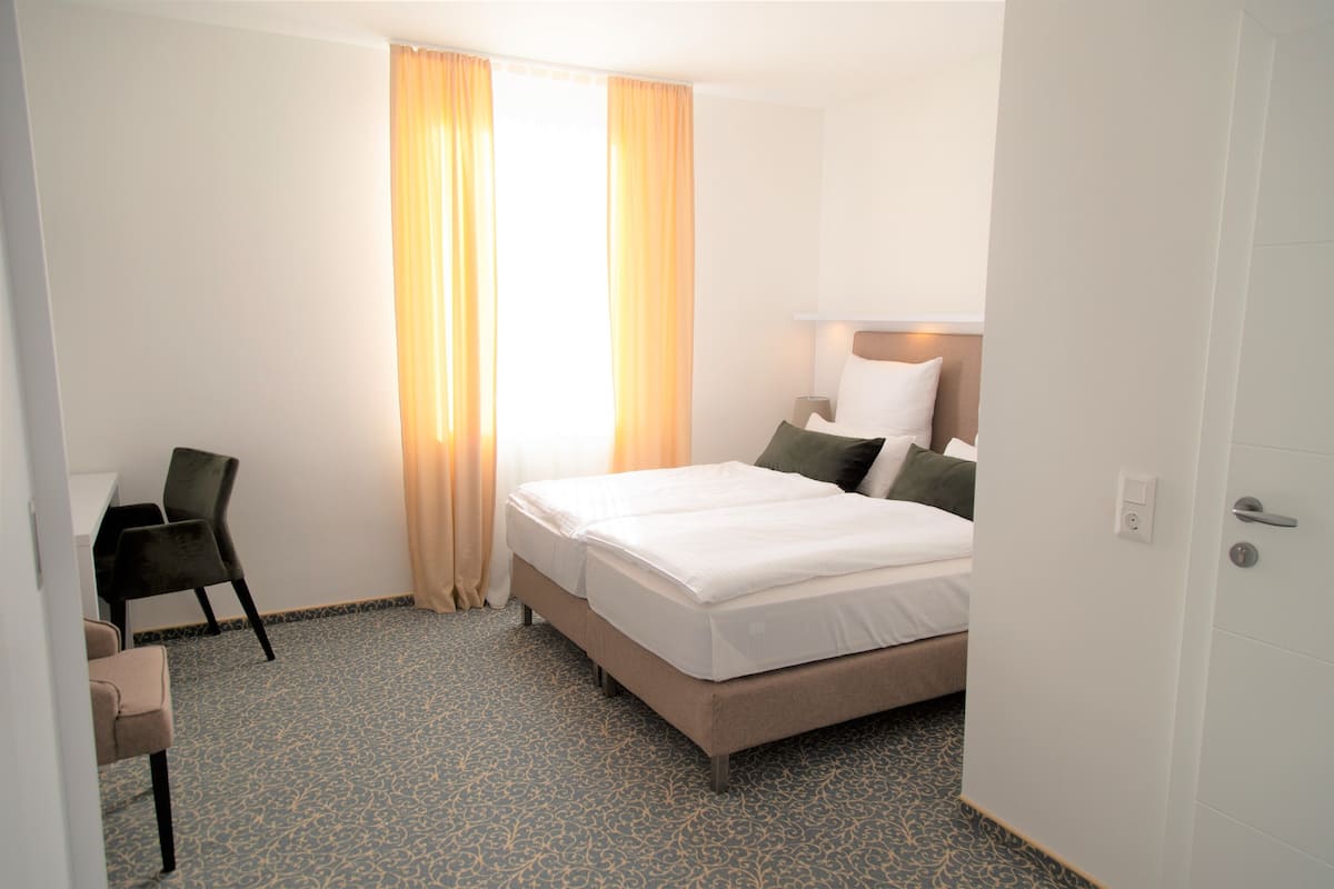 A hotel room with a bed, a desk, and a chair.