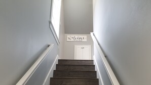 Una escalera de madera con barandillas blancas que lleva a una puerta con un letrero que dice "welcome".