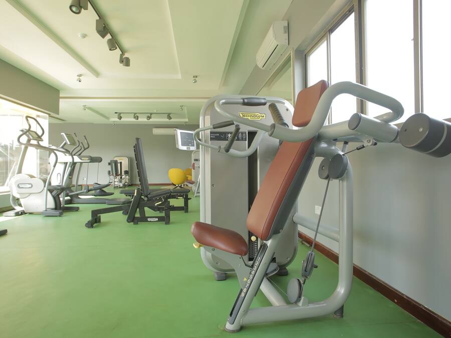 Een sportschool met trainingsapparatuur, een groene vloer en grote ramen.