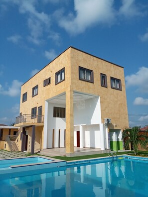 A modern two-story building with a swimming pool in front. - Cocktail and Dreams Hotel (Accra)