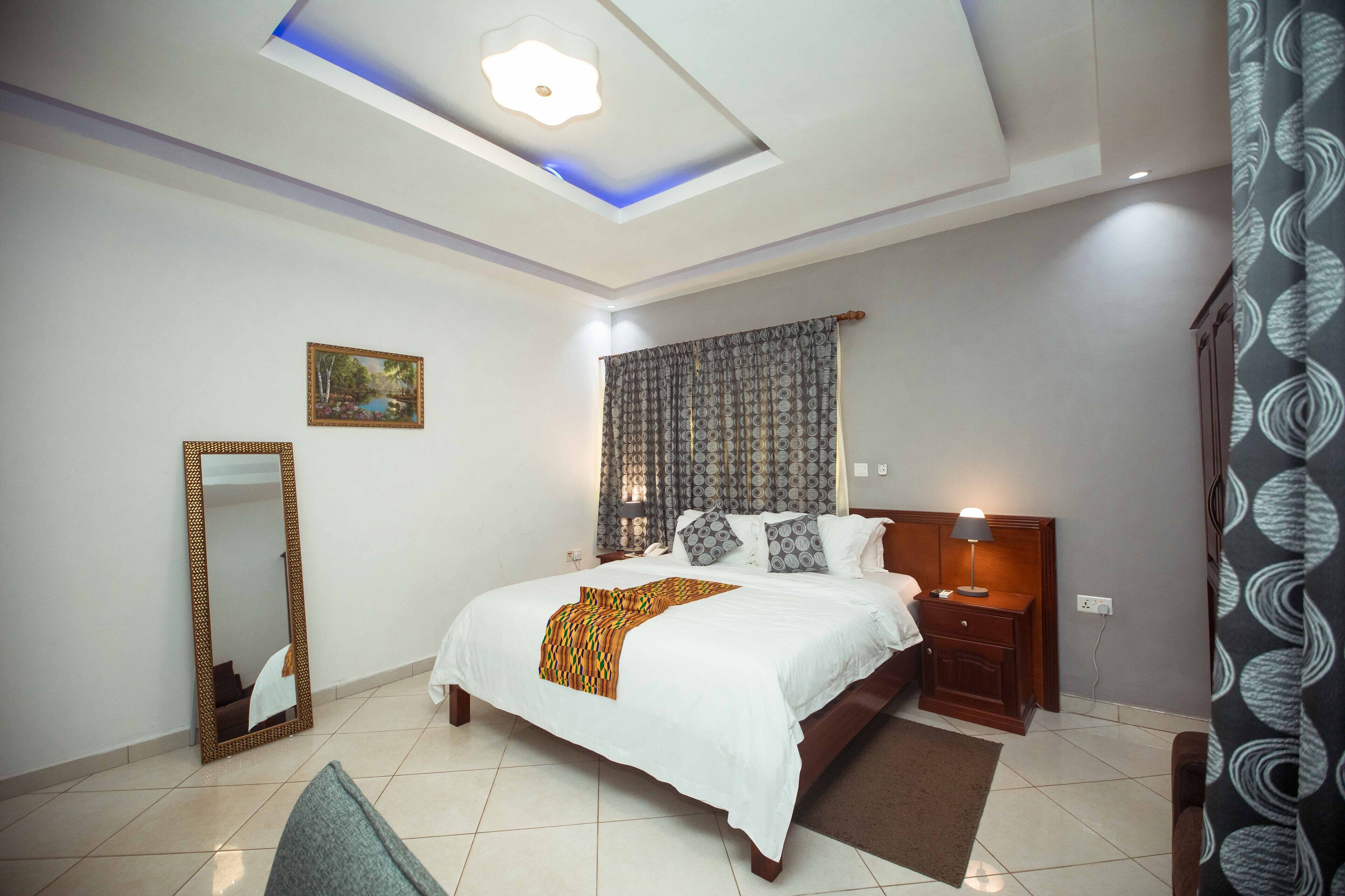 A bedroom with a bed, bedside table, lamp, and a ceiling light fixture.
