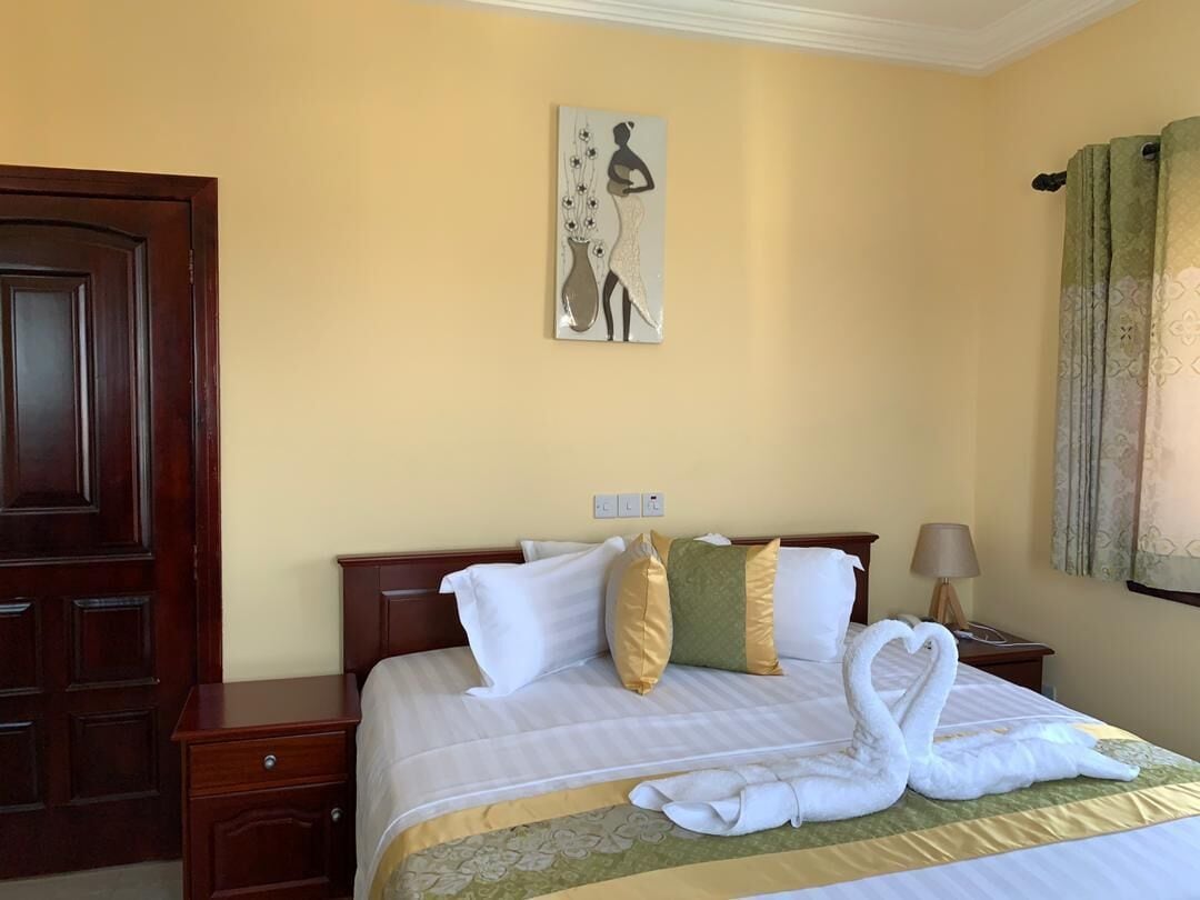 Une chambre d’hôtel avec un lit, une table de chevet, une lampe et un tableau au mur.