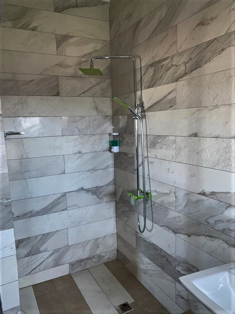 A bathroom with a shower area, marble tiles, and a sink.