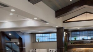 Eine geräumige Lobby mit einer Couch, Sesseln und einem kleinen runden Tisch.
