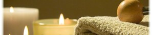 Un ambiente de spa con velas, una toalla y un objeto de madera, que sugiere un entorno relajante.