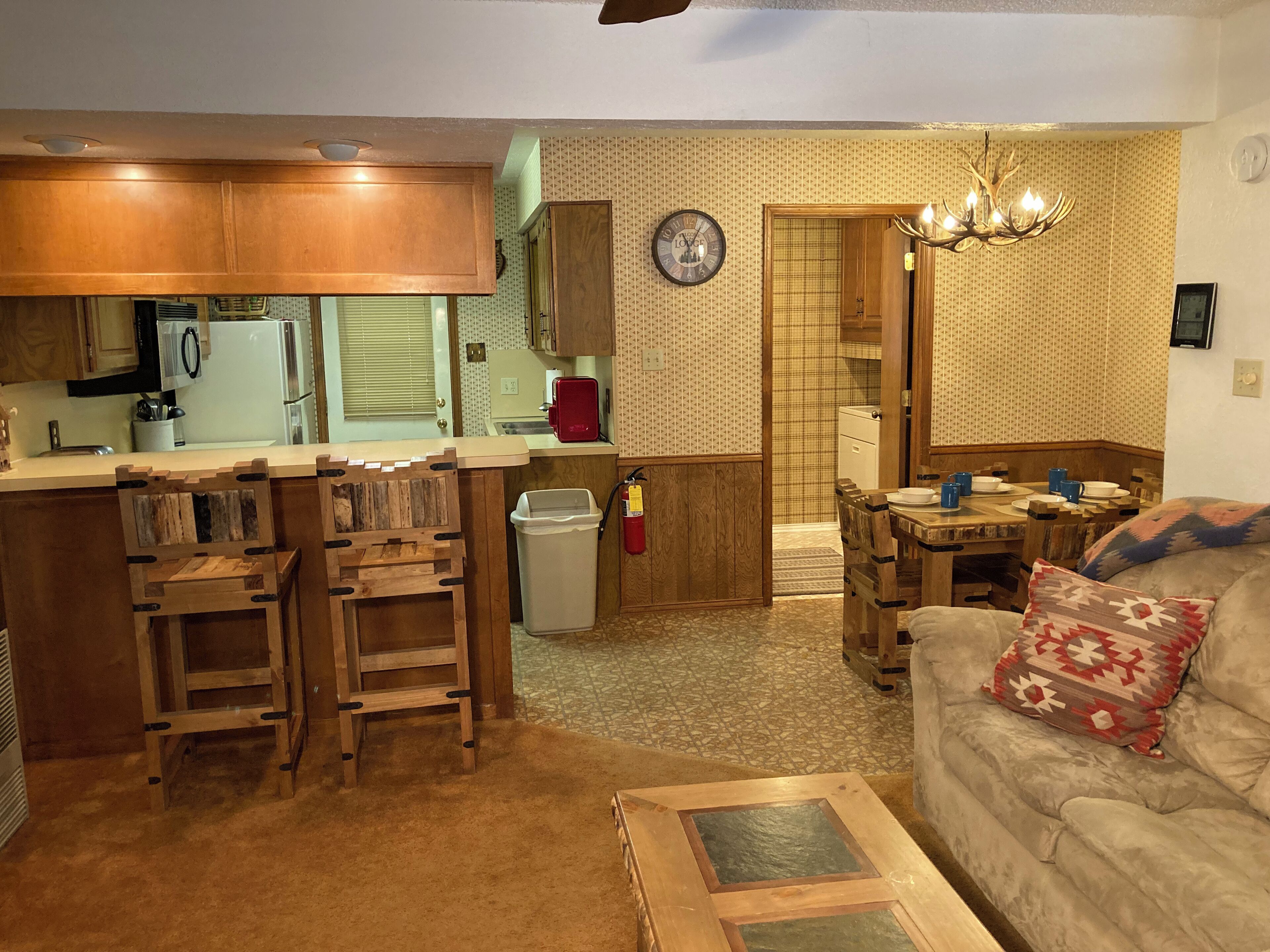 A compact living space with a kitchenette, a dining area, and a sofa with a patterned cushion.