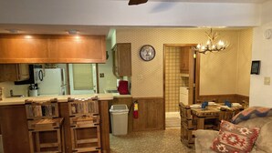 A compact living space with a kitchenette, a dining area, and a sofa with a patterned cushion.