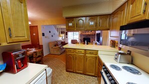 A compact kitchen with wooden cabinets, a built-in stove, and a dining area with a red retro toaster.