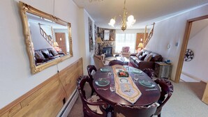 Comedor con una mesa de madera dispuesta para cuatro personas, rodeada de sillas. Un espejo grande cuelga en la pared sobre la mesa.