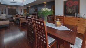 A dining area with a wooden table, chairs, and a vase of flowers.