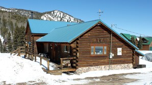 A wooden cabin with a blue roof, a wooden porch, and a sign indicating 'Wiggins'.