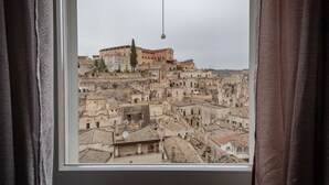 A view from a window overlooking a densely packed urban area with historic buildings and a prominent structure at the top. - Casa Adelina in the Center of the Sassi (Matera)