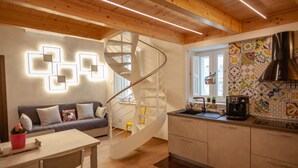 A modern kitchen with a spiral staircase, wooden ceiling, and a colorful backsplash. - Casa Adelina in the Center of the Sassi (Matera)
