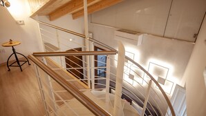 A spiral staircase with a wooden handrail and metal balusters, leading to an upper floor. - Casa Adelina in the Center of the Sassi (Matera)